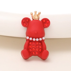 Gros plan d'un ours à couronne rouge avec des strass brillants et des perles blanches
