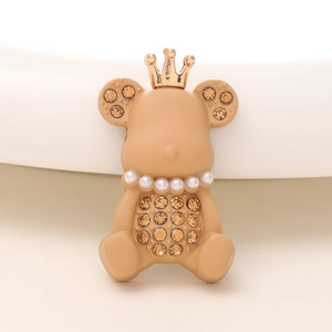 Vue macro d'un ourson marron avec couronne dorée, collier de perles et détails strass