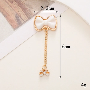 Dettaglio del ciondolo a fiocco dorato con smalto bianco e misure di 6cm per 2,3cm