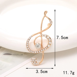 Colgante de clave de sol dorada con pedrería brillante, mide 7,5cm por 3,5cm