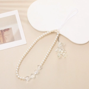 Detail of beaded phone strap featuring white pearls, heart beads, and a transparent resin bear