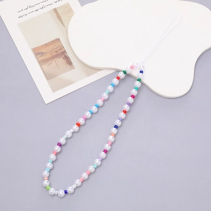 Macro detail of multi-colored acrylic beads and pearls on a vibrant mobile phone strap