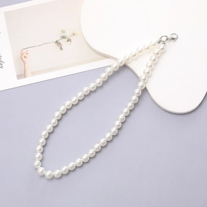Detailed macro shot of elegant white pearl beads and silver lobster clasp on a chain