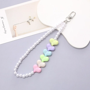 Detail of beaded phone chain with colorful heart beads and white pearls on a grey surface