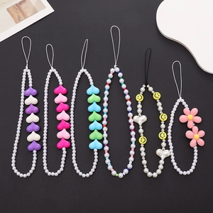 Flat lay of six colorful acrylic heart and flower beaded phone lanyards on black background