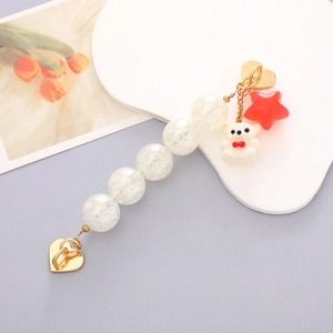 Detail of colorful acrylic phone strap with white bear and red star charm on gold heart clasp