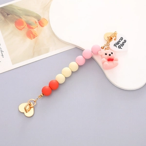 Close-up of beaded phone strap with a pink flocked bear and golden heart clasp