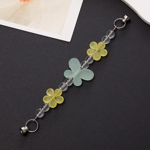 Detail view of yellow acrylic flowers and turquoise butterfly beads on a phone strap