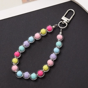 Detail of colorful beads inside acrylic charms with silver metal lobster clasps on gray surface