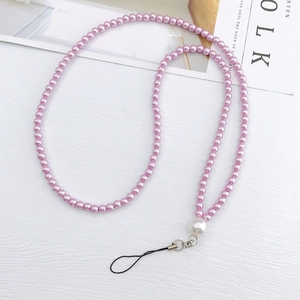 Macro detail of lavender faux pearl phone strap with metal clasp on wavy surface