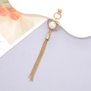 Close-up of heart-shaped gold tassel charm with pearl inlay for DIY phone case design