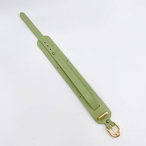 Macro detail of the grass green leather wristband strap with gold rivets and buckle