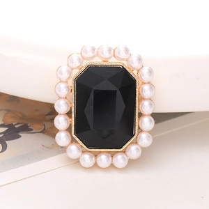 Detail van vintage gouden broche met zwarte edelsteen en witte parelrand