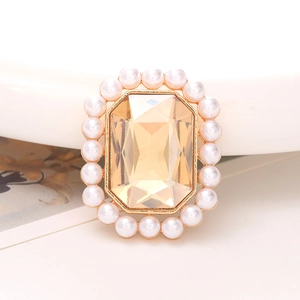 Macro-opname van champagne rechthoekige edelsteen-accessoire met parelrand en goud