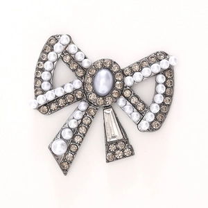 Vintage silver bow brooch with grey rhinestones and white pearls on white background