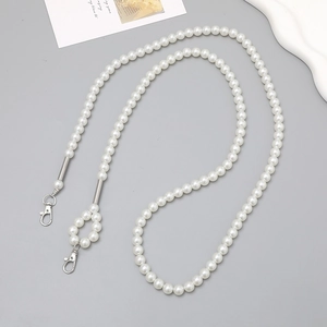Close-up of pearl crossbody chain with silver metal lobster clasps and polished connectors