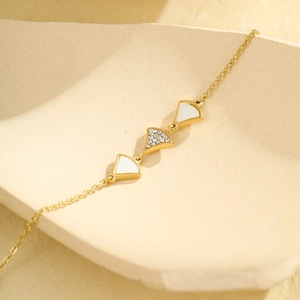 Bracelet de cheville doré élégant avec pendentifs en nacre et zircon sur un plateau