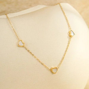 Bracelet de cheville doré élégant avec pendentifs cœurs en nacre sur un vase en céramique