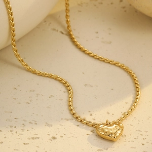 Detalle del colgante de corazón de oro 18k con textura martillada y cadena de cable