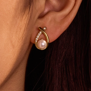 Elegant gold crossover drop earrings featuring shimmering crystals and a white pearl