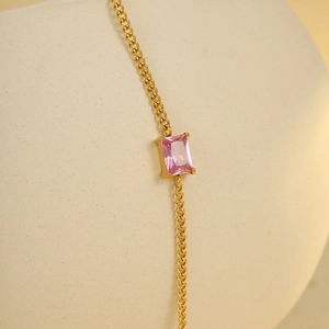 Macro shot of a rectangular pink gemstone set in a gold chain bracelet for women
