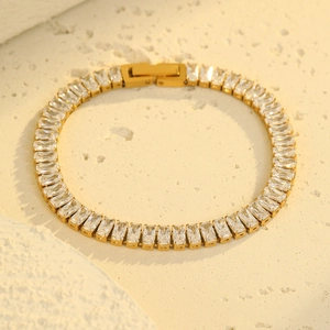 Elegantes goldenes Tennisarmband mit Zirkonia im Baguetteschliff auf Steinuntergrund