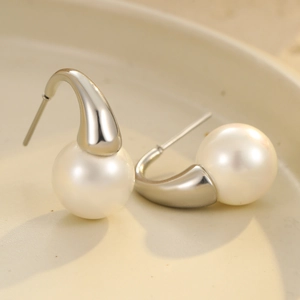 Elegant stainless steel pearl earrings with teardrop metal base on ceramic plate