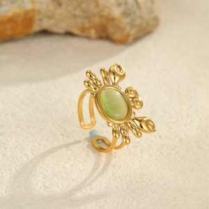 Dettaglio dell'anello a forma di granchio dorato con pietra occhio di gatto verde
