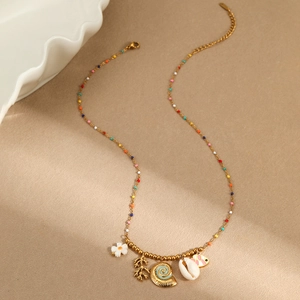 Collana a tema oceanico con perle colorate e ciondoli tropicali su sfondo di sabbia