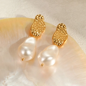 Baroque pearl earrings on golden base displayed on a natural seashell background