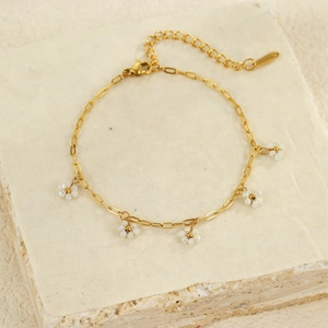 Close-up of golden beaded flower charms on a delicate stainless steel bracelet