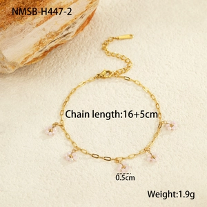 Detail view of gold beaded chain bracelet featuring five delicate white flower pendants