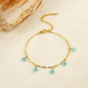 Detailed close-up of golden anklet with five light blue flower charms and extension chain