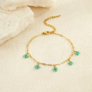 Detailed shot of golden link bracelet featuring mint green beaded flower charms and clasp