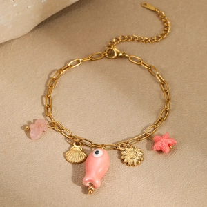 Dettaglio di bracciale a maglie dorate con ciondoli a stella marina e conchiglie