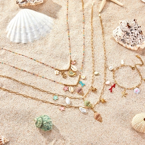 Set de joyas bohemias con colgantes de conchas y estrellas de mar en fondo de playa