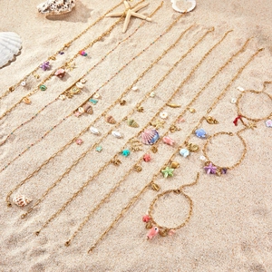 Set di gioielli oceanici dorati con stelle marine e conchiglie sulla sabbia estiva
