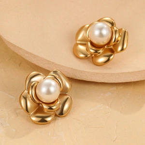 Elegant gold camellia flower pearl stud earrings displayed on a minimalist stone tray
