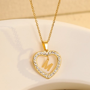 Macro shot of gold heart necklace with M letter pendant and micro-set cubic zirconia stones