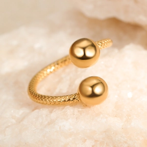 Macro shot of gold adjustable ring with sphere ends on white mineral stone