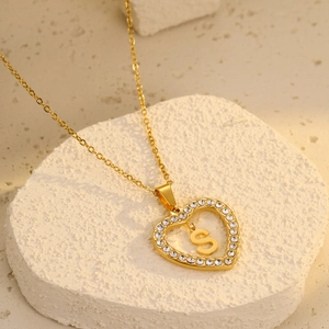 Macro detail of 18K gold heart pendant with sparkling cubic zirconia and letter S