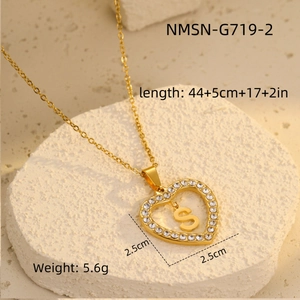 Detailed macro view of gold heart pendant with sparkling zircons and letter S engraving