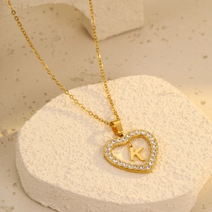 Macro detail of gold-plated heart pendant with zircon pavé and initial letter K