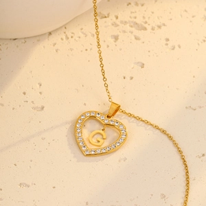 Detailed view of gold heart pendant with letter G and sparkling zircon stones