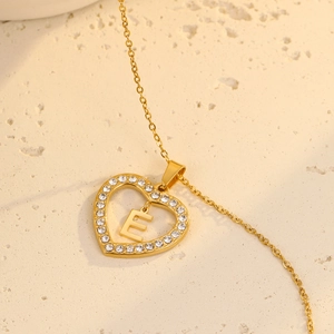 Macro shot of gold heart pendant necklace with zircon border and letter E detail