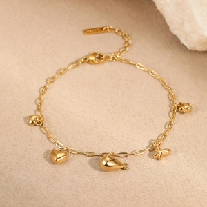 Bracelet doré en acier inoxydable avec pendentifs papillon, cœur et étoile sur fond pierre