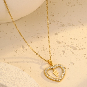 Detailed shot of gold heart pendant necklace with letter F and zircon stones