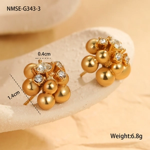 Detail view of golden cluster stud earrings with zircon stones on white stone props