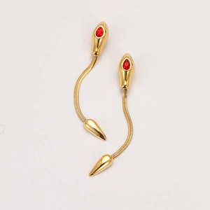 Detail of snake earrings with long golden chains and red teardrop gemstones