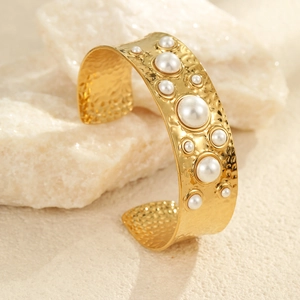 Détail d'un bracelet manchette doré avec texture martelée et perles blanches élégantes